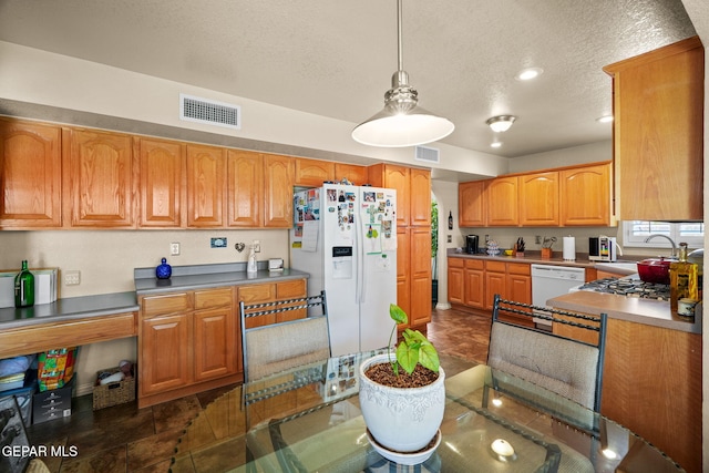 18986 Armington Dr, Horizon City, TX 79928 - kitchen featuring white appliances, a textured ceiling, pendant lighting, brown cabinetry, and recessed lighting
