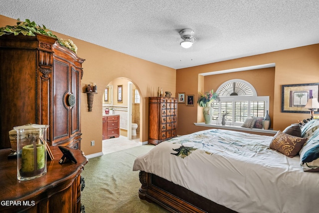 18986 Armington Dr, Horizon City, TX 79928 - bedroom with arched walkways, carpet flooring, a textured ceiling, ensuite bathroom, and ceiling fan