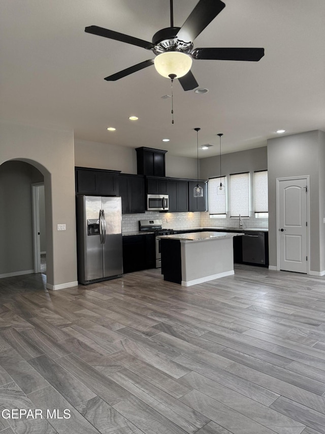 229 Epsom Dr, El Paso, TX 79928 - kitchen with appliances with stainless steel finishes, dark cabinetry, a center island, a ceiling fan, and light countertops