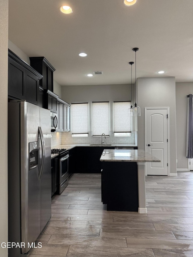 229 Epsom Dr, El Paso, TX 79928 - kitchen featuring stainless steel appliances, dark cabinets, light stone counters, a center island, and recessed lighting