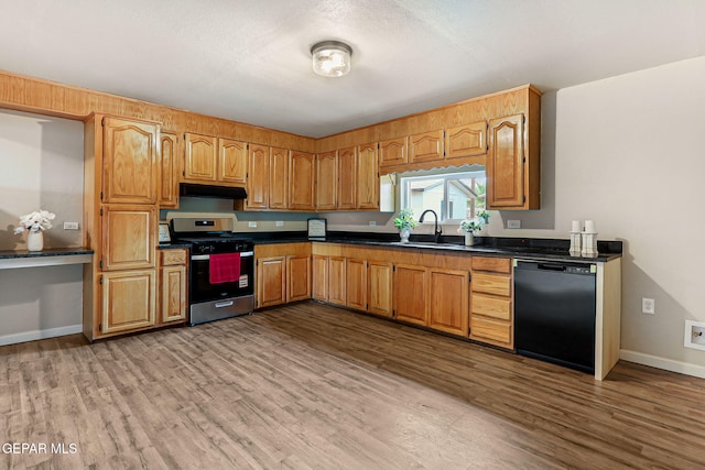 125 N Nevarez Rd, Socorro, TX 79927 - kitchen with black dishwasher, stainless steel gas range, under cabinet range hood, wood finished floors, and dark countertops