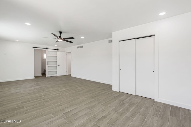 5841 Burning Tree Dr, El Paso, TX 79912 - unfurnished bedroom with a barn door, light wood-style floors, recessed lighting, and ceiling fan