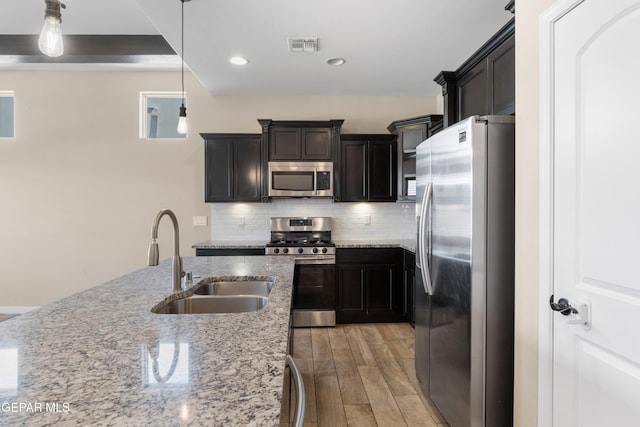 13597 Gatton St, El Paso, TX 79928 - kitchen with stainless steel appliances, backsplash, light stone countertops, light wood finished floors, and pendant lighting