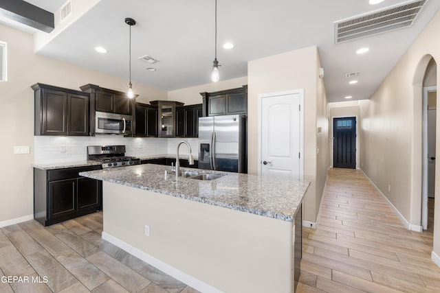 13597 Gatton St, El Paso, TX 79928 - kitchen featuring appliances with stainless steel finishes, backsplash, light stone countertops, and light wood-style floors