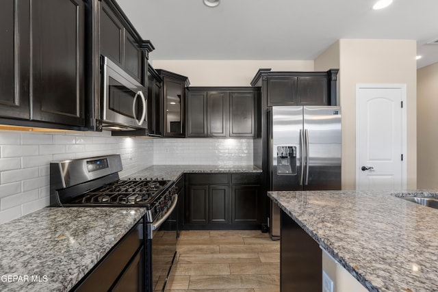 13597 Gatton St, El Paso, TX 79928 - kitchen featuring appliances with stainless steel finishes, light stone counters, tasteful backsplash, recessed lighting, and light wood-style flooring