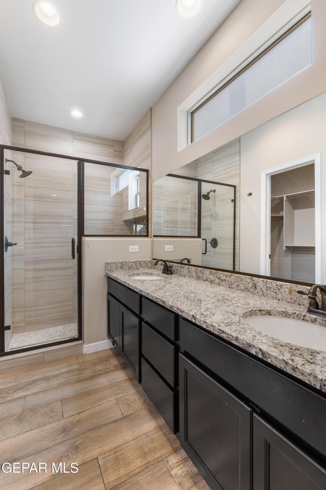 13597 Gatton St, El Paso, TX 79928 - bathroom with a stall shower, double vanity, wood finished floors, and a spacious closet
