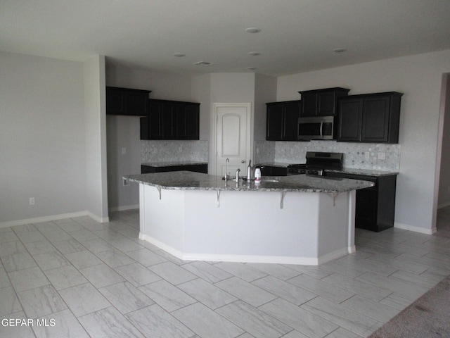 2813 Mike Price Dr, El Paso, TX 79938 - kitchen with stainless steel microwave, range with gas stovetop, backsplash, and a spacious island