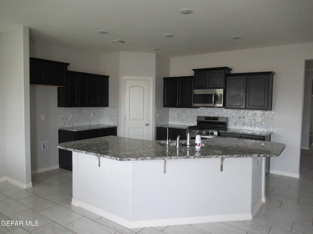 2813 Mike Price Dr, El Paso, TX 79938 - kitchen featuring appliances with stainless steel finishes, decorative backsplash, stone countertops, and a large island