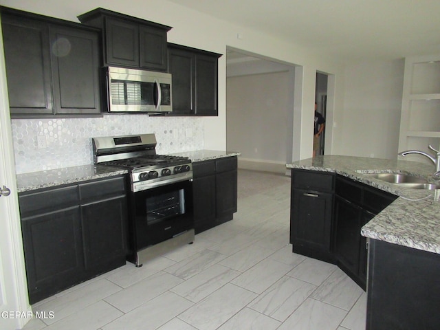 2813 Mike Price Dr, El Paso, TX 79938 - kitchen with appliances with stainless steel finishes, dark cabinetry, decorative backsplash, and light stone counters