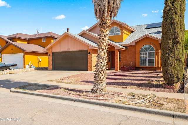 11960 Francis Scobee Dr, El Paso, TX 79936 - view of front of home featuring a garage, solar panels, driveway, roof with shingles, and brick siding