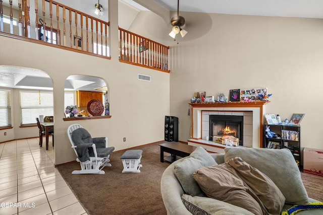 11960 Francis Scobee Dr, El Paso, TX 79936 - carpeted living room featuring tile patterned floors, a ceiling fan, a tiled fireplace, and high vaulted ceiling