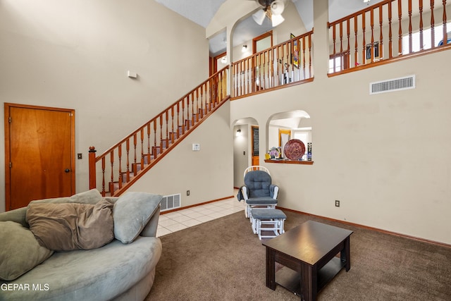11960 Francis Scobee Dr, El Paso, TX 79936 - carpeted living area with a towering ceiling, a ceiling fan, stairway, arched walkways, and tile patterned flooring