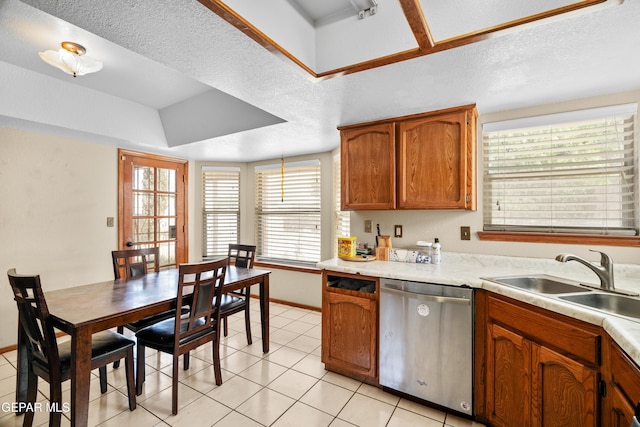 11960 Francis Scobee Dr, El Paso, TX 79936 - kitchen featuring stainless steel dishwasher, light countertops, light tile patterned flooring, brown cabinetry, and a textured ceiling