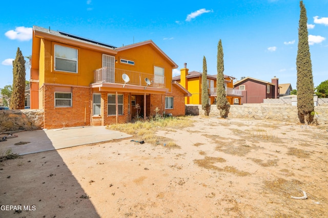 11960 Francis Scobee Dr, El Paso, TX 79936 - rear view of property featuring a balcony, roof mounted solar panels, and a patio area