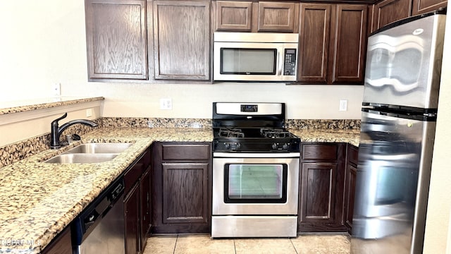 14207 Ranier Point Dr, El Paso, TX 79938 - kitchen featuring stainless steel appliances, dark brown cabinetry, light stone countertops, and light tile patterned floors