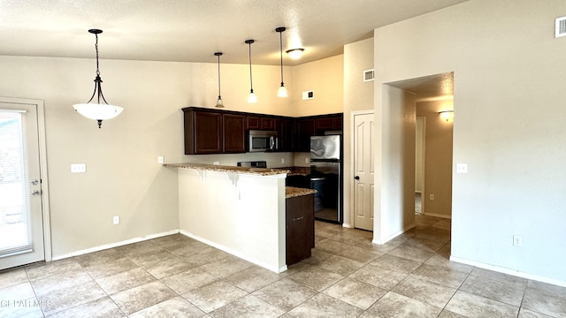 14207 Ranier Point Dr, El Paso, TX 79938 - kitchen featuring stainless steel microwave, refrigerator, a peninsula, light stone counters, and a kitchen bar