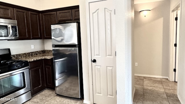 14207 Ranier Point Dr, El Paso, TX 79938 - kitchen featuring appliances with stainless steel finishes, dark brown cabinets, dark stone countertops, and light tile patterned floors