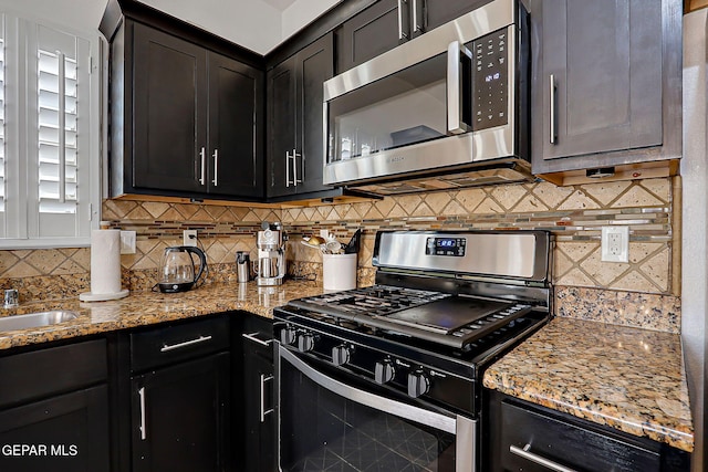 3143 Red Maple, El Paso, TX 79938 - kitchen with appliances with stainless steel finishes, decorative backsplash, light stone counters, and dark cabinetry