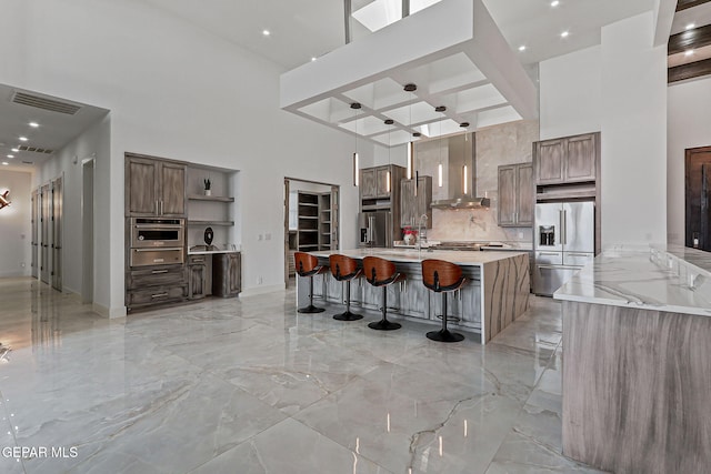 6325 Camino Pinon, El Paso, TX 79932 - kitchen featuring a high ceiling, appliances with stainless steel finishes, wall chimney range hood, open shelves, and a warming drawer