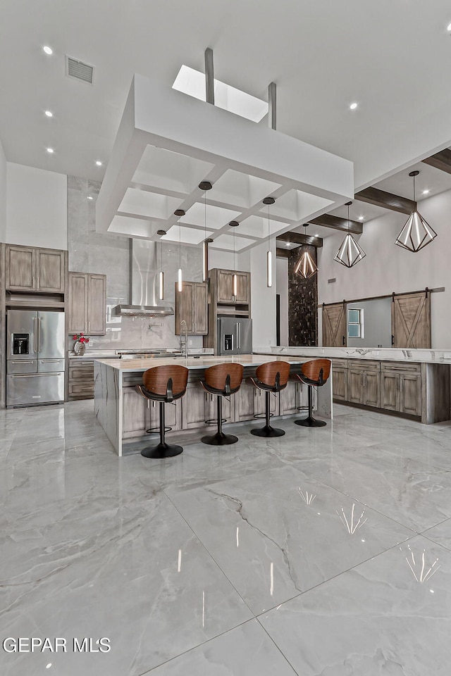 6325 Camino Pinon, El Paso, TX 79932 - kitchen with high end refrigerator, coffered ceiling, wall chimney exhaust hood, a kitchen bar, and light countertops