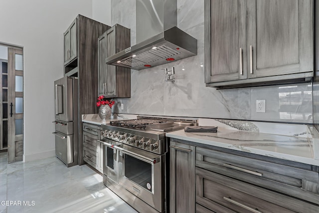 6325 Camino Pinon, El Paso, TX 79932 - kitchen with wall chimney exhaust hood, high end appliances, backsplash, light stone countertops, and light marble finish floors