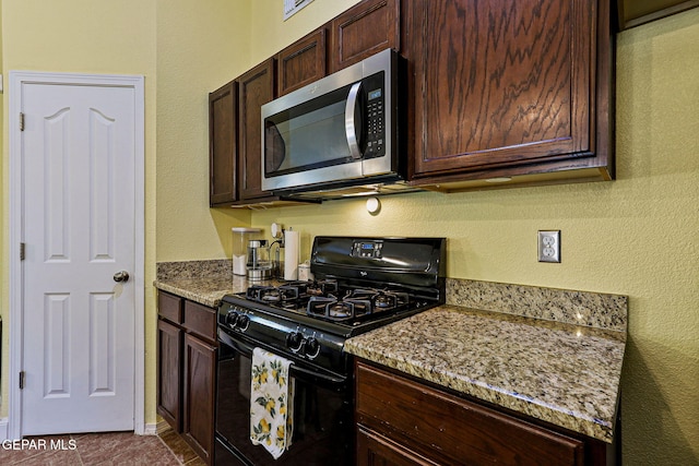 11652 Ochre Bluff Ln, El Paso, TX 79934 - kitchen featuring stainless steel microwave, black gas stove, a textured wall, dark brown cabinetry, and light stone counters