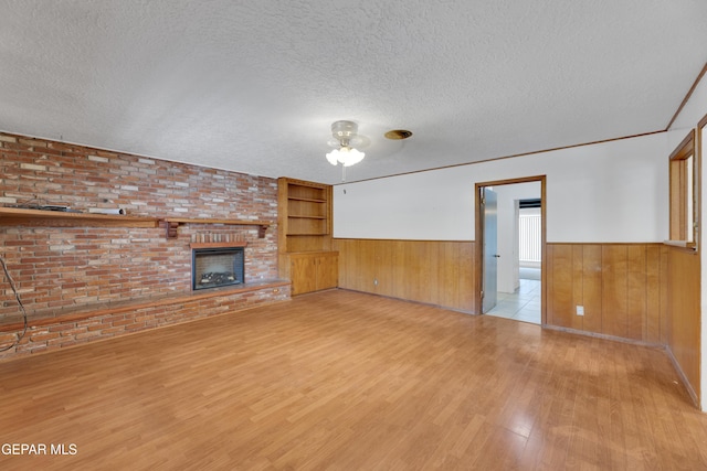3313 Dublin Rd, El Paso, TX 79925 - unfurnished living room with wood finished floors, a wainscoted wall, a textured ceiling, wood walls, and ceiling fan