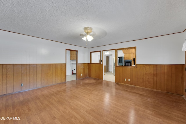 3313 Dublin Rd, El Paso, TX 79925 - unfurnished living room with a wainscoted wall, ceiling fan, wood finished floors, a textured ceiling, and wooden walls