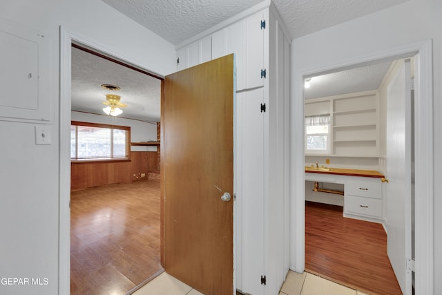 3313 Dublin Rd, El Paso, TX 79925 - corridor featuring a textured ceiling, light wood-style flooring, and wooden walls
