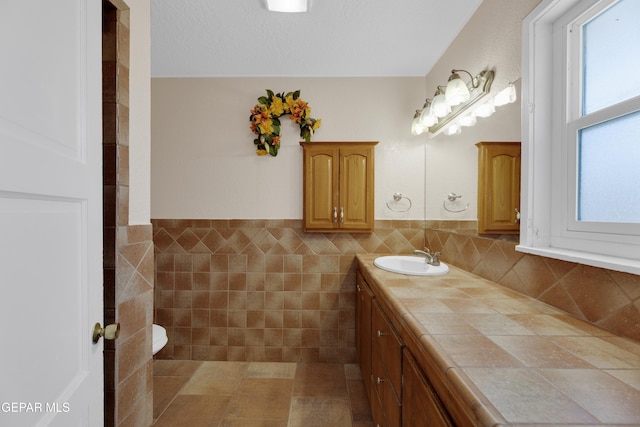 3313 Dublin Rd, El Paso, TX 79925 - bathroom with double vanity, tile walls, and wainscoting