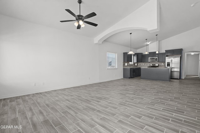 14373 Nick Drahos Ln, Horizon City, TX 79928 - unfurnished living room featuring ceiling fan, arched walkways, light wood finished floors, and high vaulted ceiling