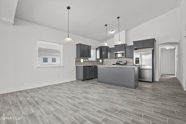 14373 Nick Drahos Ln, Horizon City, TX 79928 - kitchen with stainless steel appliances, high vaulted ceiling, decorative backsplash, arched walkways, and light wood finished floors