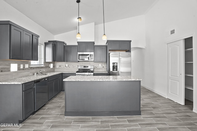 14373 Nick Drahos Ln, Horizon City, TX 79928 - kitchen featuring appliances with stainless steel finishes, high vaulted ceiling, decorative backsplash, light wood-type flooring, and a center island