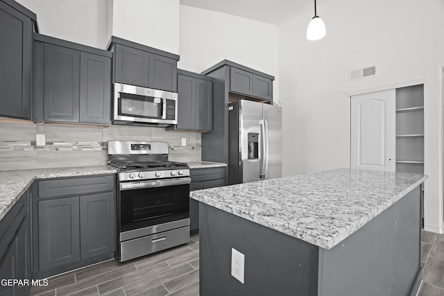 14373 Nick Drahos Ln, Horizon City, TX 79928 - kitchen with stainless steel appliances, wood finish floors, decorative backsplash, light stone countertops, and a towering ceiling