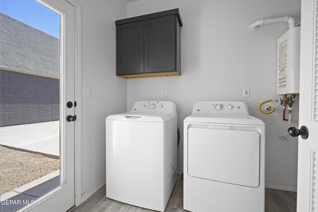 14373 Nick Drahos Ln, Horizon City, TX 79928 - laundry area featuring cabinet space, washing machine and clothes dryer, tankless water heater, and wood tiled floors
