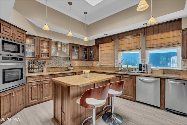 981 Vereda Del Valle Ave, El Paso, TX 79932 - kitchen with appliances with stainless steel finishes, wall chimney range hood, tasteful backsplash, and hanging light fixtures