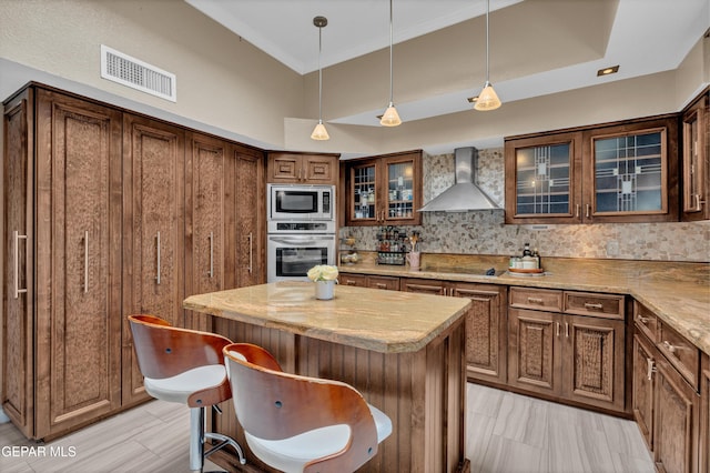 981 Vereda Del Valle Ave, El Paso, TX 79932 - kitchen featuring wall chimney exhaust hood, appliances with stainless steel finishes, ornamental molding, decorative backsplash, and a kitchen island