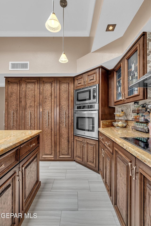 981 Vereda Del Valle Ave, El Paso, TX 79932 - kitchen featuring stainless steel appliances, light stone countertops, pendant lighting, glass insert cabinets, and brown cabinetry