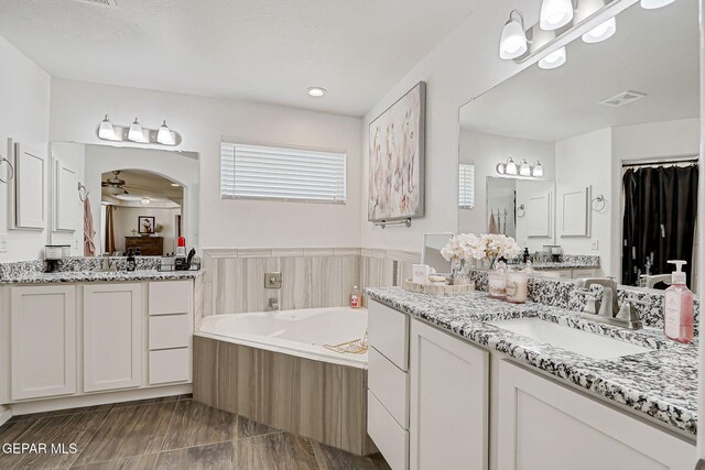 13847 Alamito Creek Ave, Clint, TX 79836 - bathroom featuring a garden tub, two vanities, and a stall shower