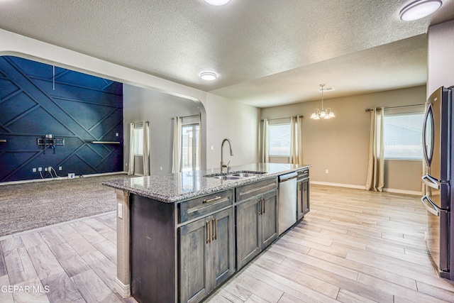 14936 Ted Banks Ave, El Paso, TX 79938 - kitchen featuring stainless steel appliances, light wood-style flooring, light stone countertops, a textured ceiling, and arched walkways