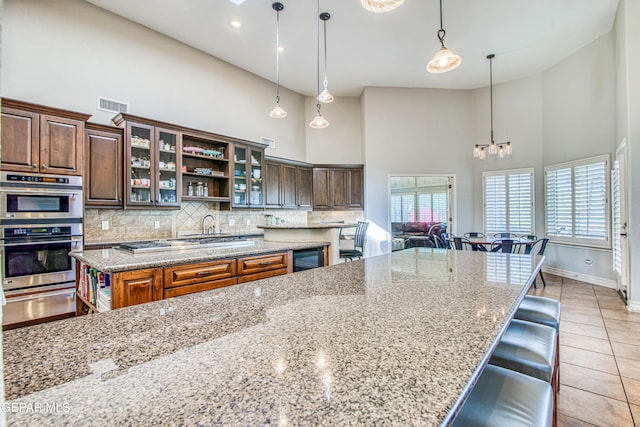 1348 Franklin Wind Place, El Paso, TX 79912 - kitchen featuring a high ceiling, a warming drawer, backsplash, open shelves, and light tile patterned floors