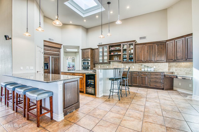 1348 Franklin Wind Place, El Paso, TX 79912 - kitchen featuring a high ceiling, beverage cooler, a skylight, a breakfast bar, and decorative backsplash