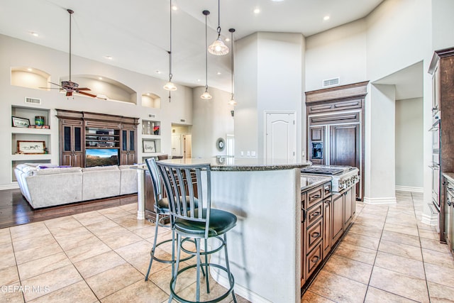 1348 Franklin Wind Place, El Paso, TX 79912 - kitchen featuring a high ceiling, built in shelves, a kitchen island, ceiling fan, and a breakfast bar area