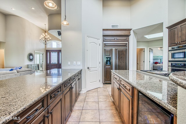 1348 Franklin Wind Place, El Paso, TX 79912 - kitchen with high vaulted ceiling, appliances with stainless steel finishes, light stone counters, wine cooler, and a chandelier