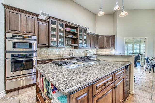 1348 Franklin Wind Place, El Paso, TX 79912 - kitchen featuring open shelves, a warming drawer, appliances with stainless steel finishes, a center island, and a high ceiling