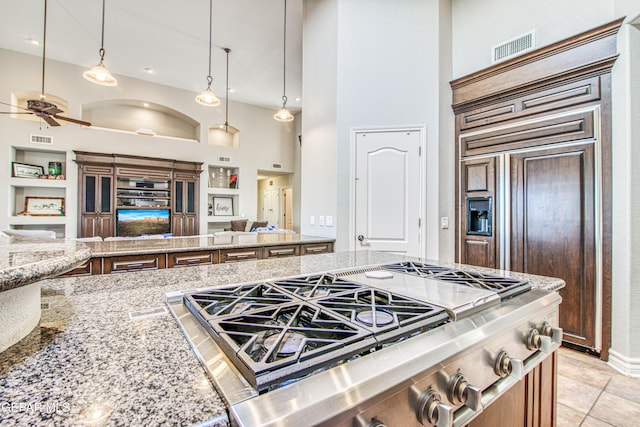 1348 Franklin Wind Place, El Paso, TX 79912 - kitchen with open floor plan, built in shelves, a ceiling fan, a towering ceiling, and light stone counters