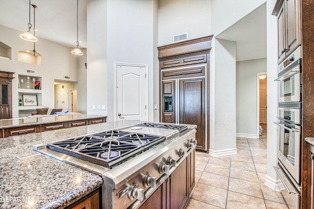 1348 Franklin Wind Place, El Paso, TX 79912 - kitchen with stainless steel appliances, a warming drawer, a towering ceiling, light stone counters, and light tile patterned floors