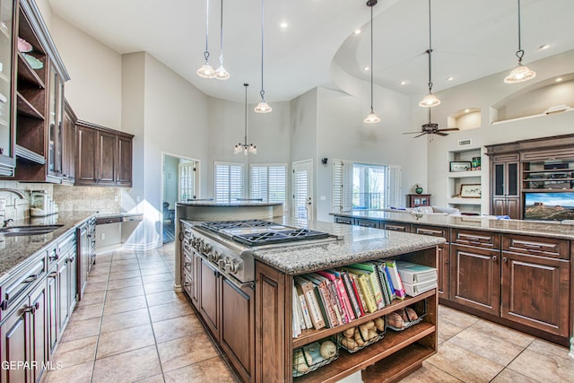 1348 Franklin Wind Place, El Paso, TX 79912 - kitchen with open shelves, stainless steel gas cooktop, a large island, a towering ceiling, and dark brown cabinets
