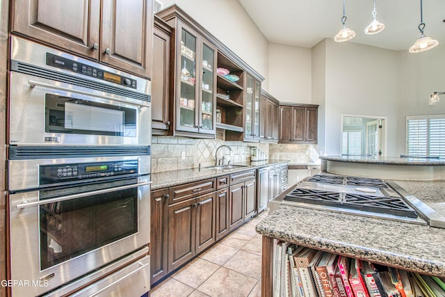 1348 Franklin Wind Place, El Paso, TX 79912 - kitchen featuring appliances with stainless steel finishes, tasteful backsplash, dark brown cabinets, a warming drawer, and a towering ceiling