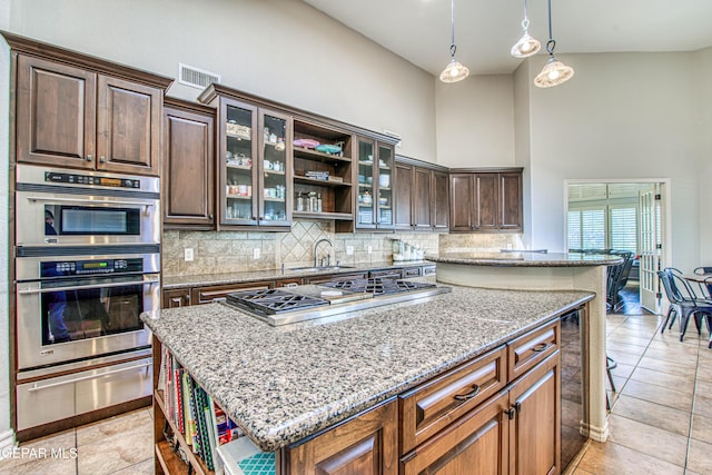 1348 Franklin Wind Place, El Paso, TX 79912 - kitchen featuring a warming drawer, open shelves, a center island, backsplash, and a high ceiling